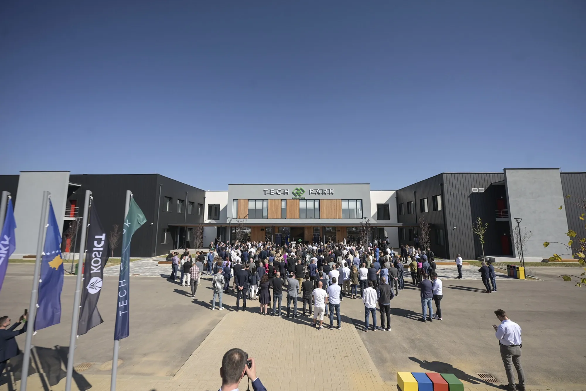 Opening day at Tech Park Prishtina — a crowd gathered in front of the building under Kosovo and Tech Park flags.
