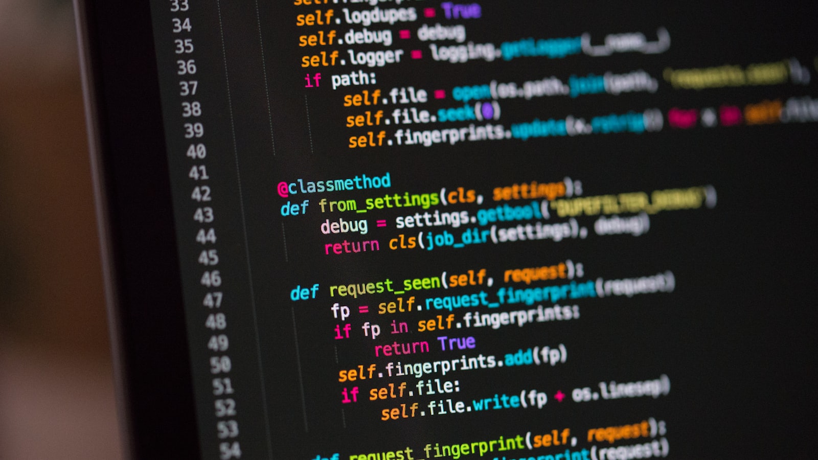 Een software-engineer werkt over twee monitors vol code in een geconcentreerde werkruimte.