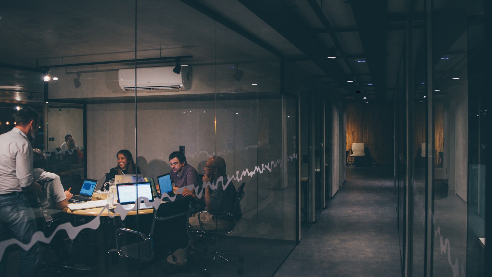 Een klein softwareteam werkt samen rond een tafel met laptops in een licht kantoor.