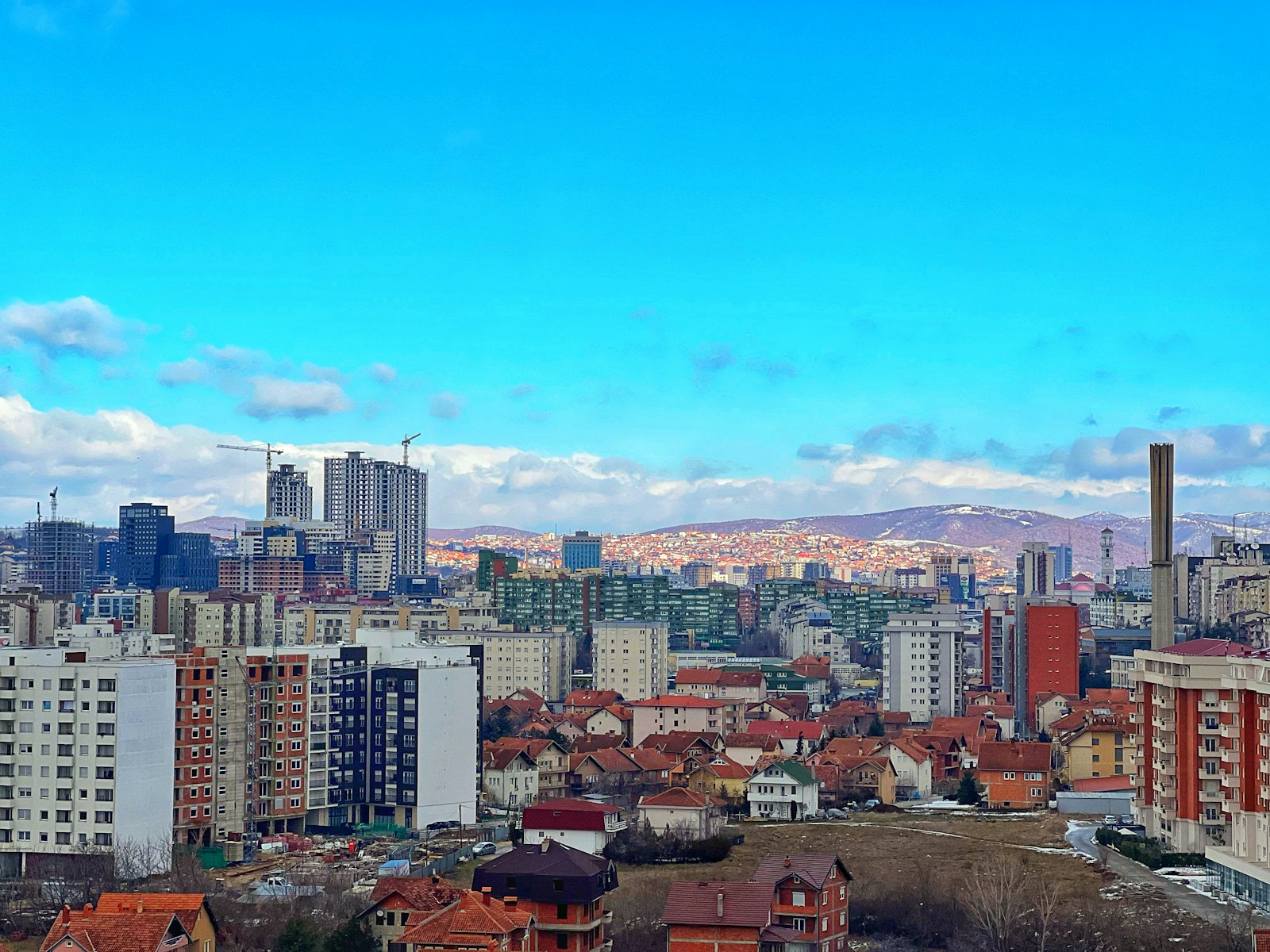 Een uitzicht over Prishtina, Kosovo, met de stad uitgespreid onder een wijde lucht.